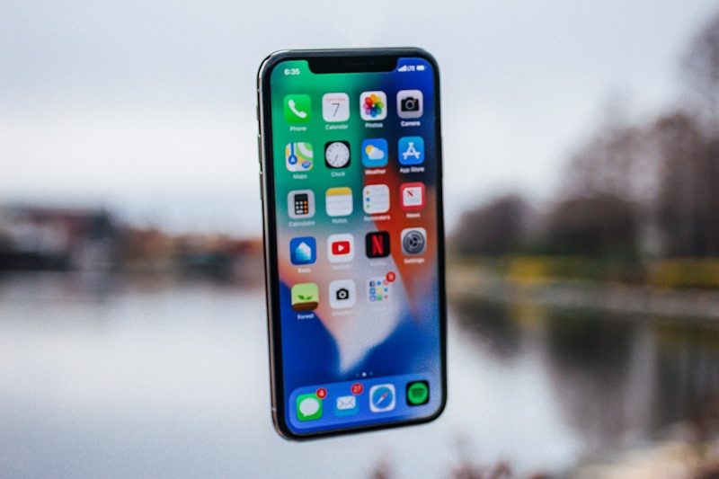 silver iPhone X floating over open palm